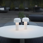 The white Bellhop Cordless Lamp from FLOS in an outdoor living space on top of a coffee table.