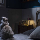 The burgundy Fleur Portable Table Lamp from Foscarini in a primary bedroom beside the bed on top of a bedside table.