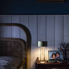 The sage green Fleur Portable Table Lamp from Foscarini in a bedroom on a bedside table next to a photograph.