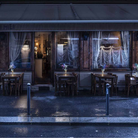 The sage green Fleur Portable Table Lamp from Foscarini in front of a restaurant on cafe tables.