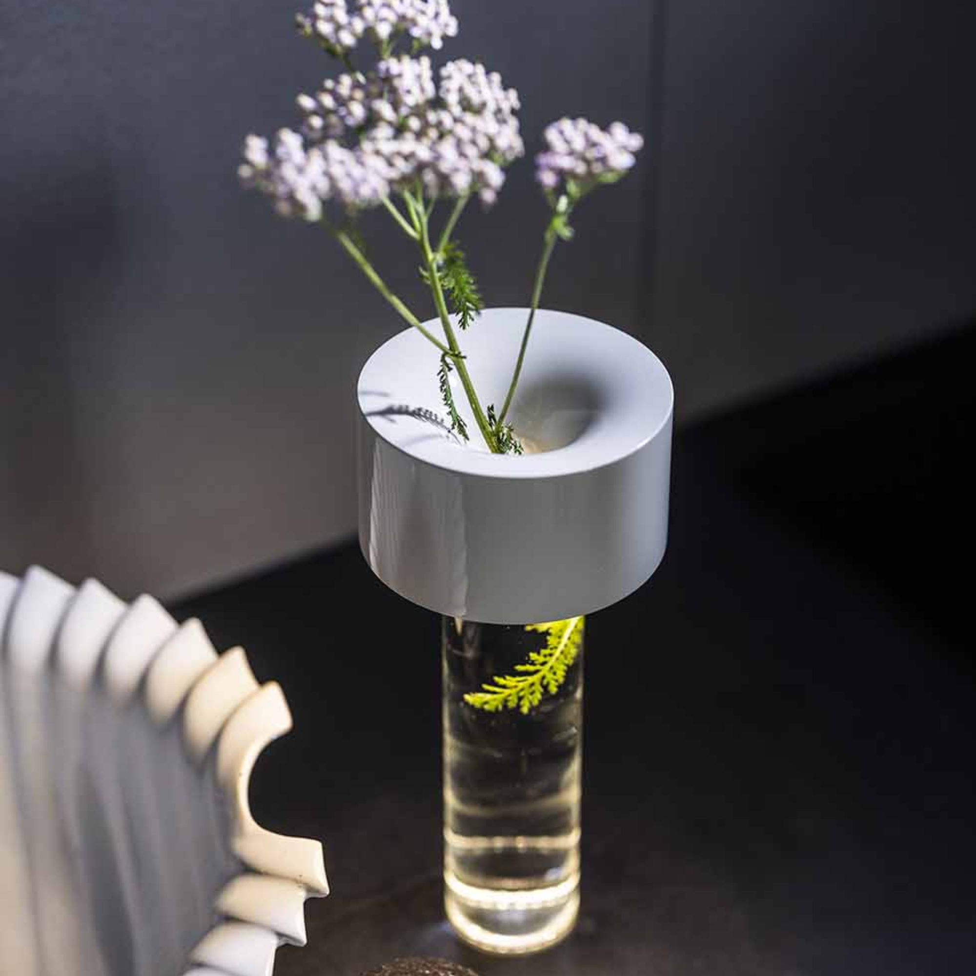 The white Fleur Portable Table Lamp from Foscarini in a lounge on top of a table.