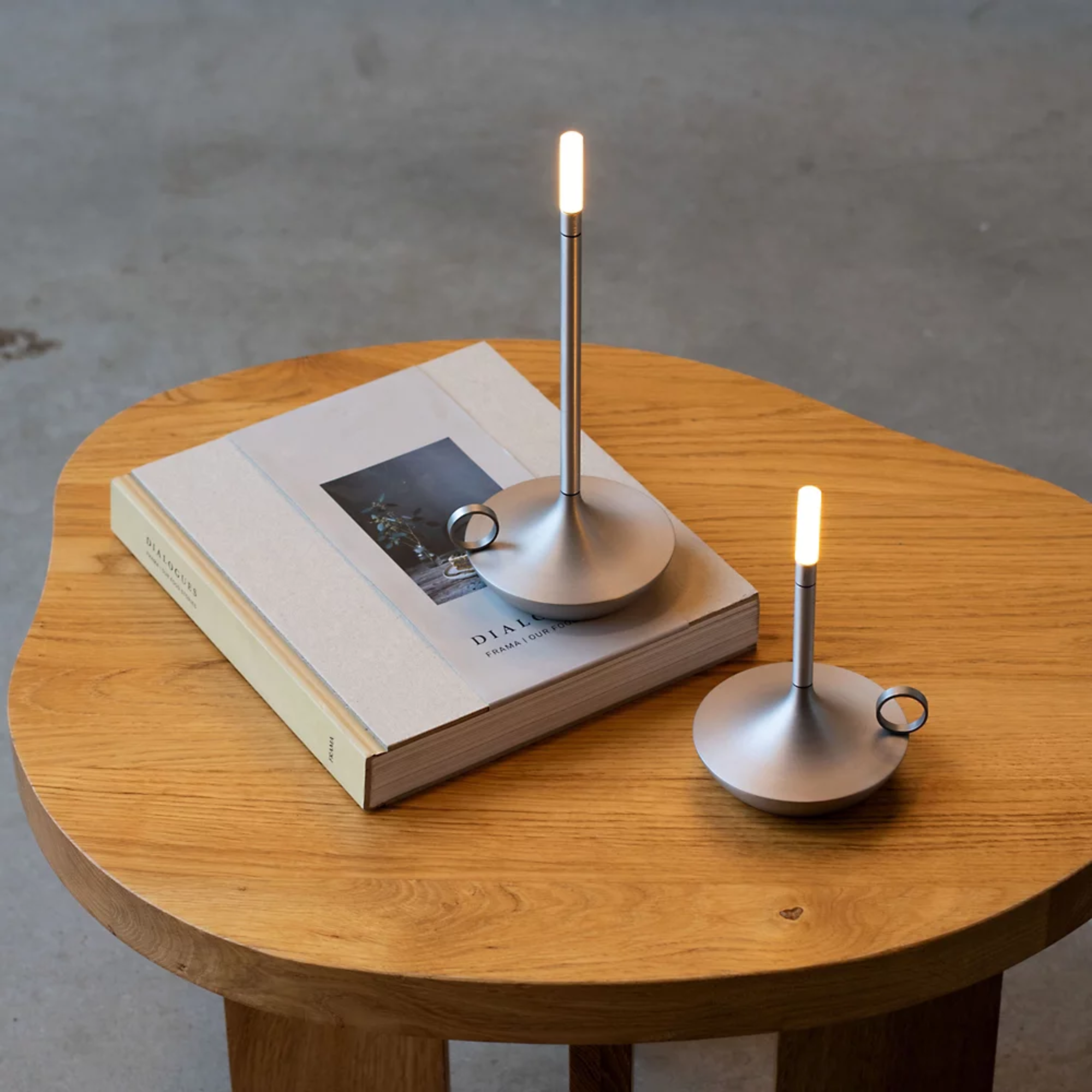 The aluminum Wick Cordless Lamp from Graypants in a home office on top of an end table.