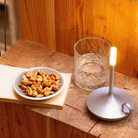 The aluminum Wick Cordless Lamp from Graypants in a kitchen and dining space on top of a wooden surface.