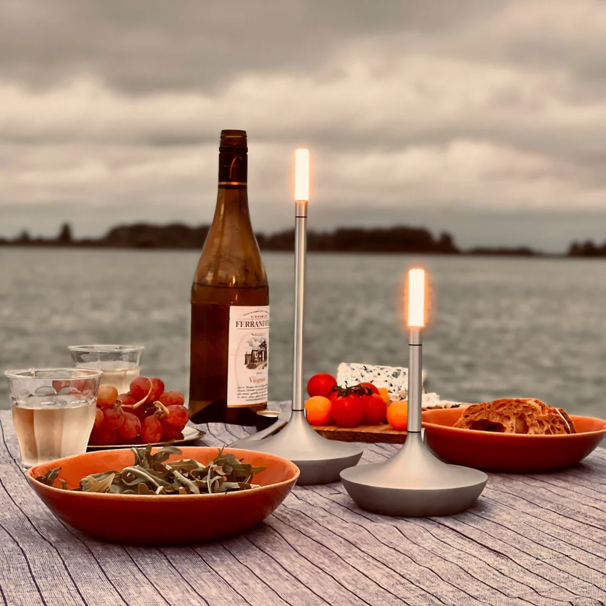 The aluminum Wick Cordless Lamp from Graypants used outdoors on a table for alfresco dining.