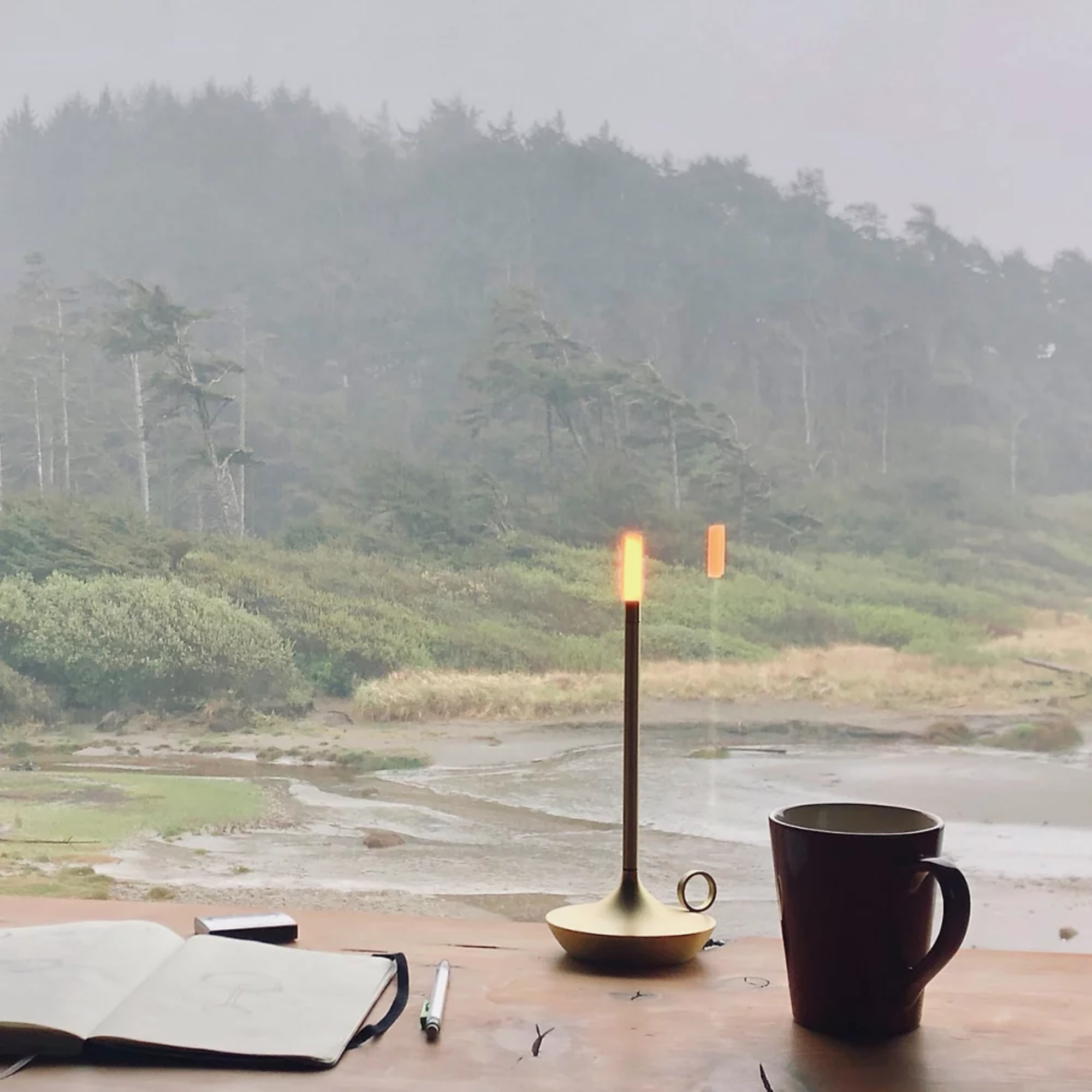 The brass Wick Cordless Lamp from Graypants in a living room overlooking a beach. all-groups
