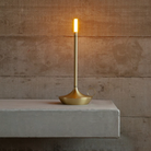 The brass Wick Cordless Lamp from Graypants in a lounge on top of a shelf.