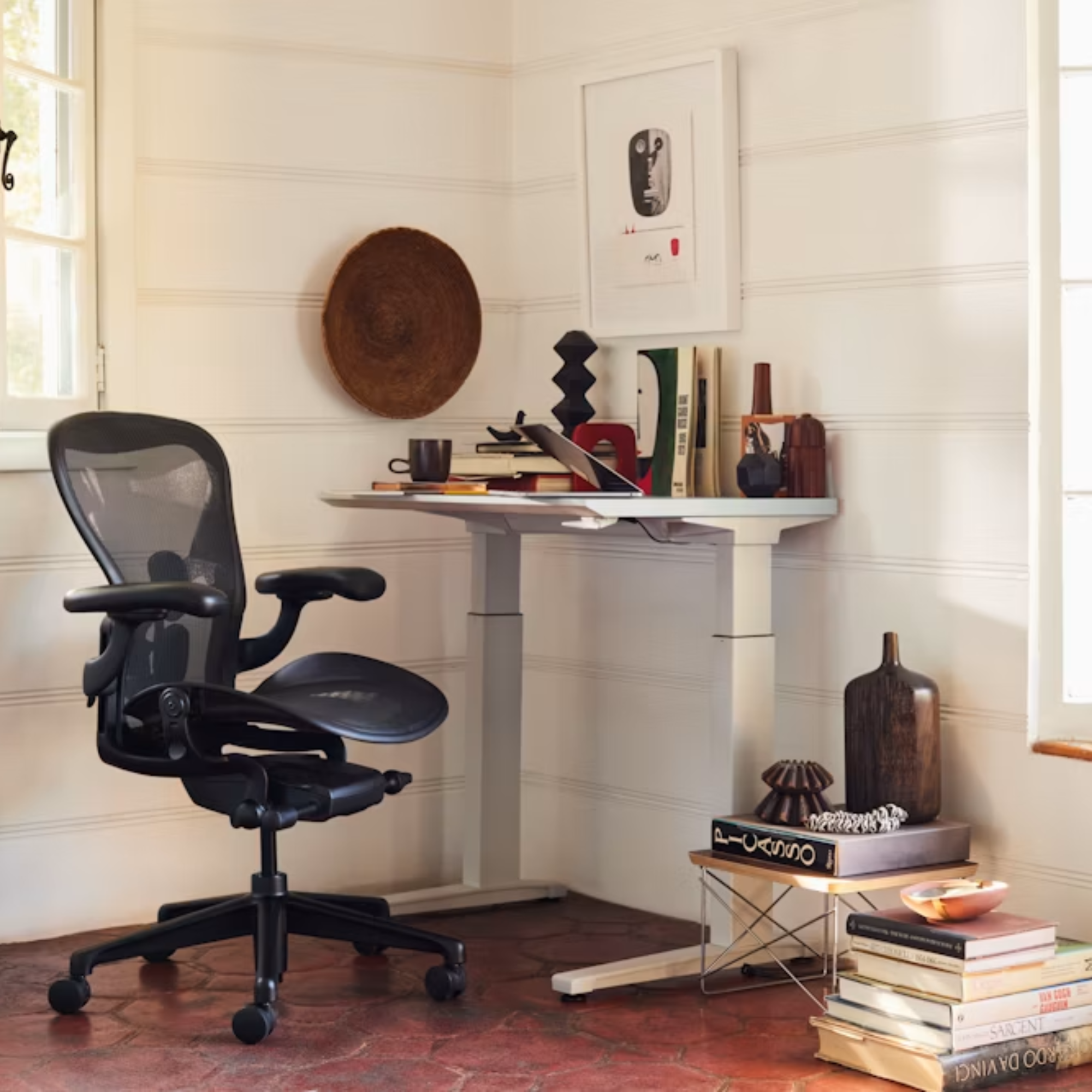 The Aeron Office Chair from Herman Miller shown in an art studio in front of a sit to stand desk.