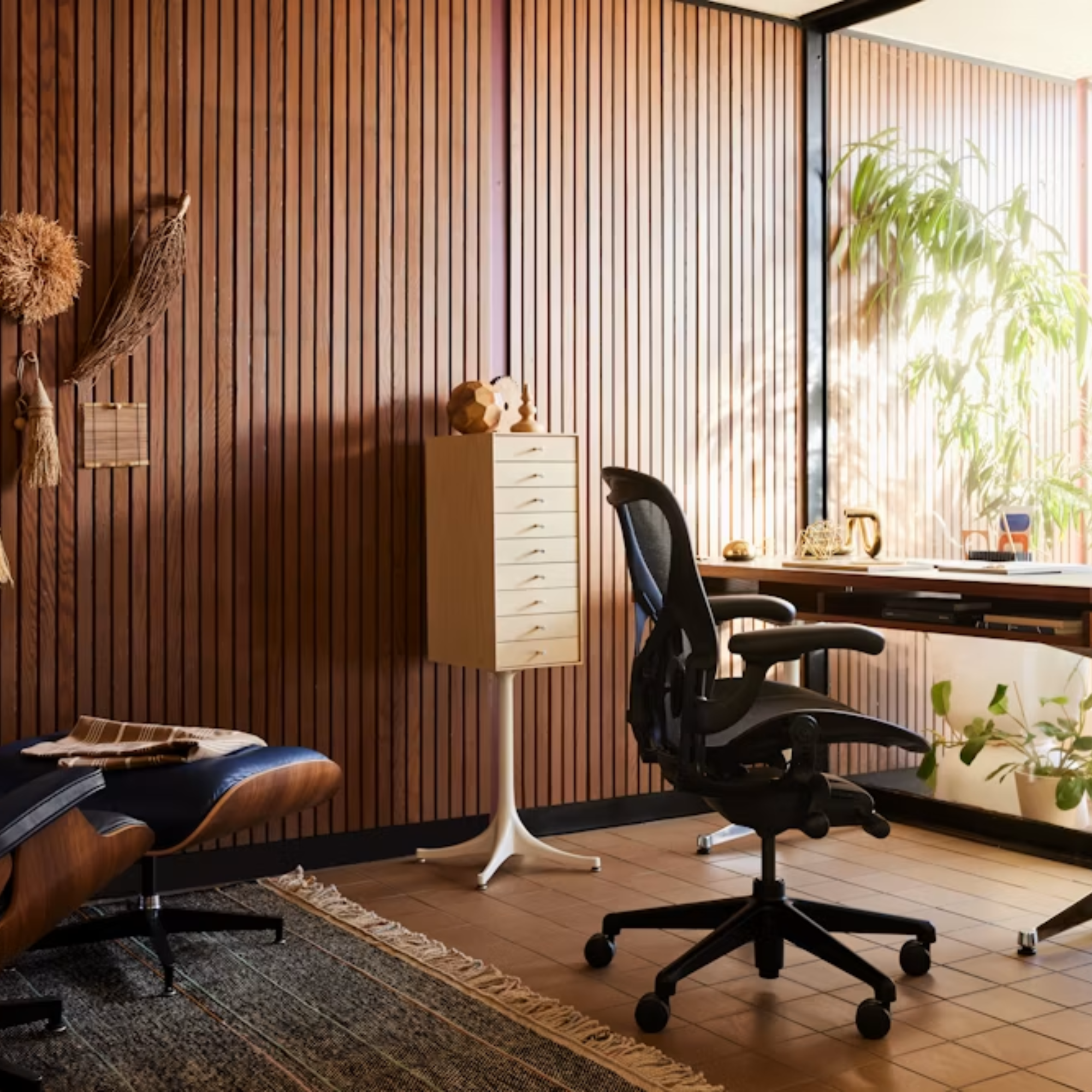 The Aeron Office Chair from Herman Miller shown in a business lounge in front of the Eames Lounge Chair and Ottoman.