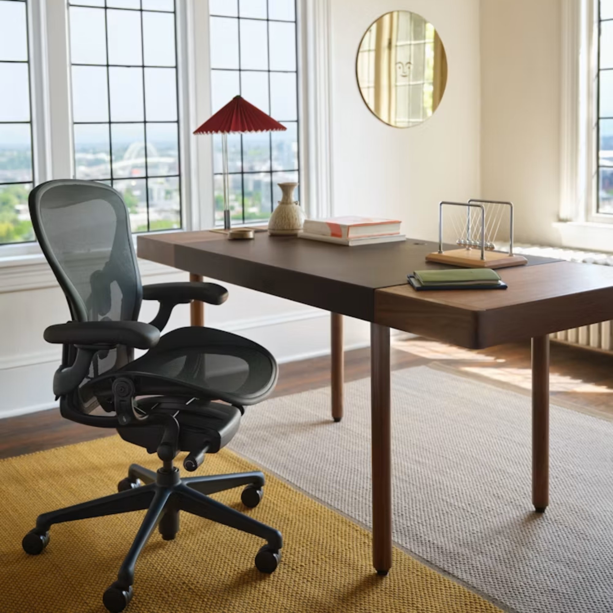 The black and onyx Aeron Office Chair from Herman Miller in a commercial office in front of a leather wrapped desk with decor.