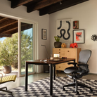 The Aeron Office Chair from Herman Miller shown in a family area in front of a desk with a laptop, with a storage unit in the corner.