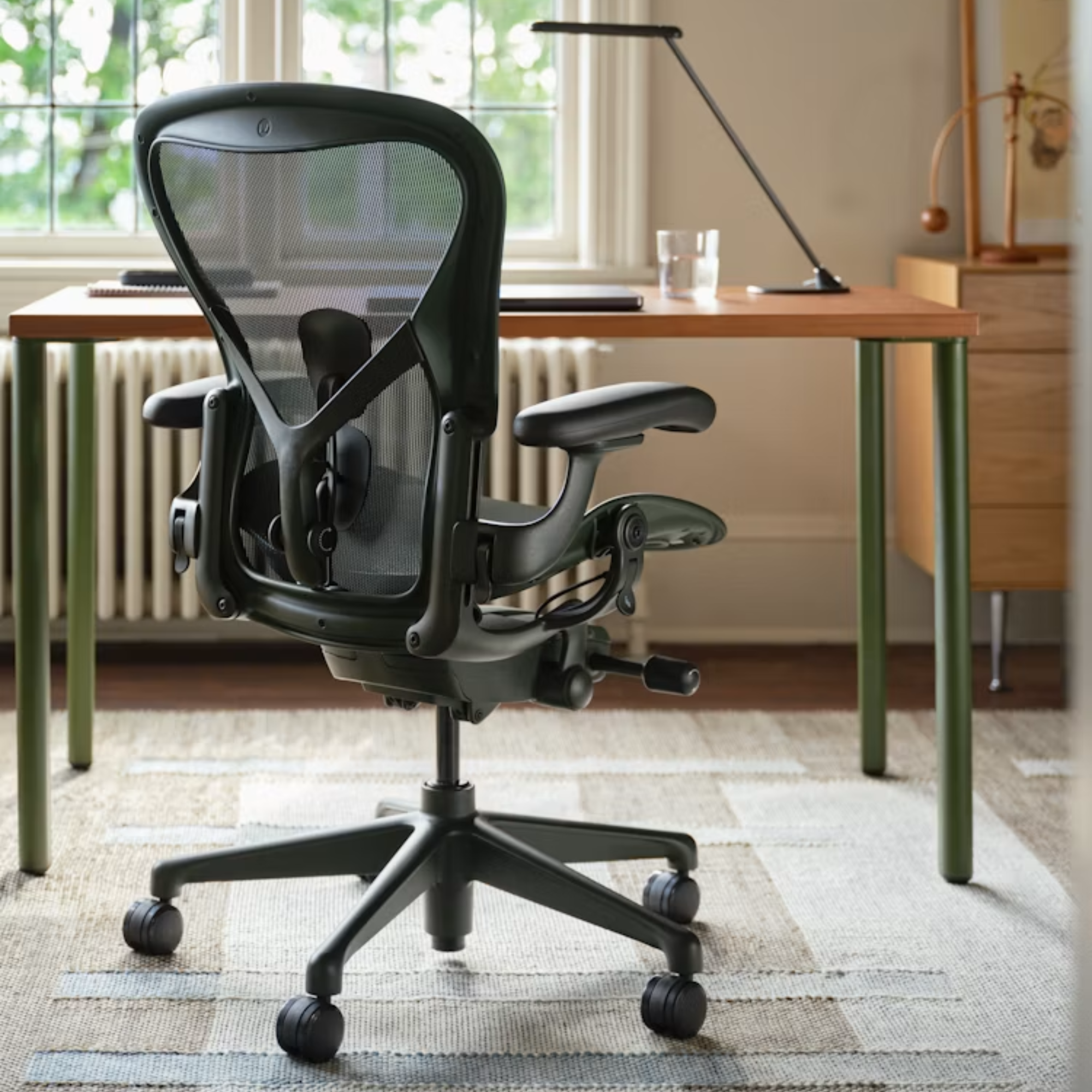 The Aeron Office Chair from Herman Miller in a home office in front of a wooden desk on top of a rug.