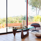 The walnut Noguchi Table from Herman Miller in a business lounge beside a lounge chair.