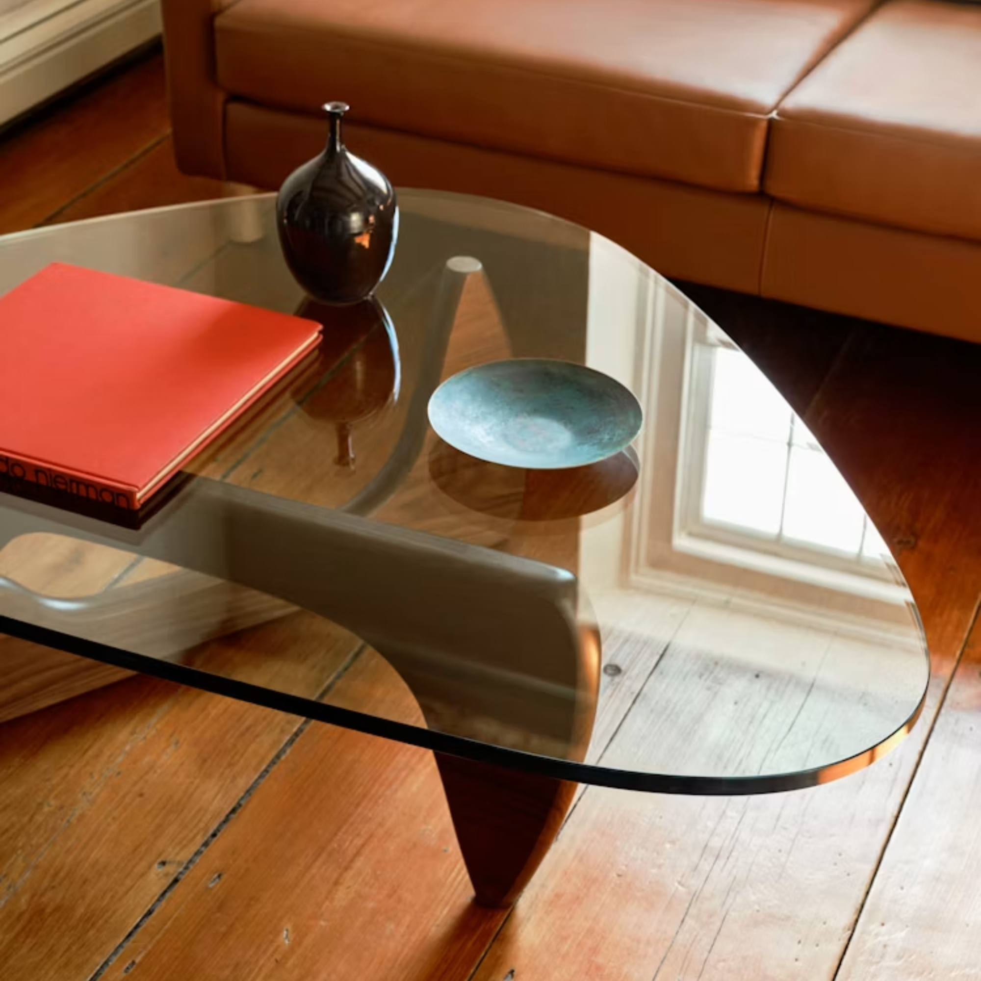The walnut Noguchi Table from Herman Miller in a business office in front of a couch.