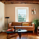 The walnut Noguchi Table from Herman Miller in a living space next to a floor lamp and sofa.