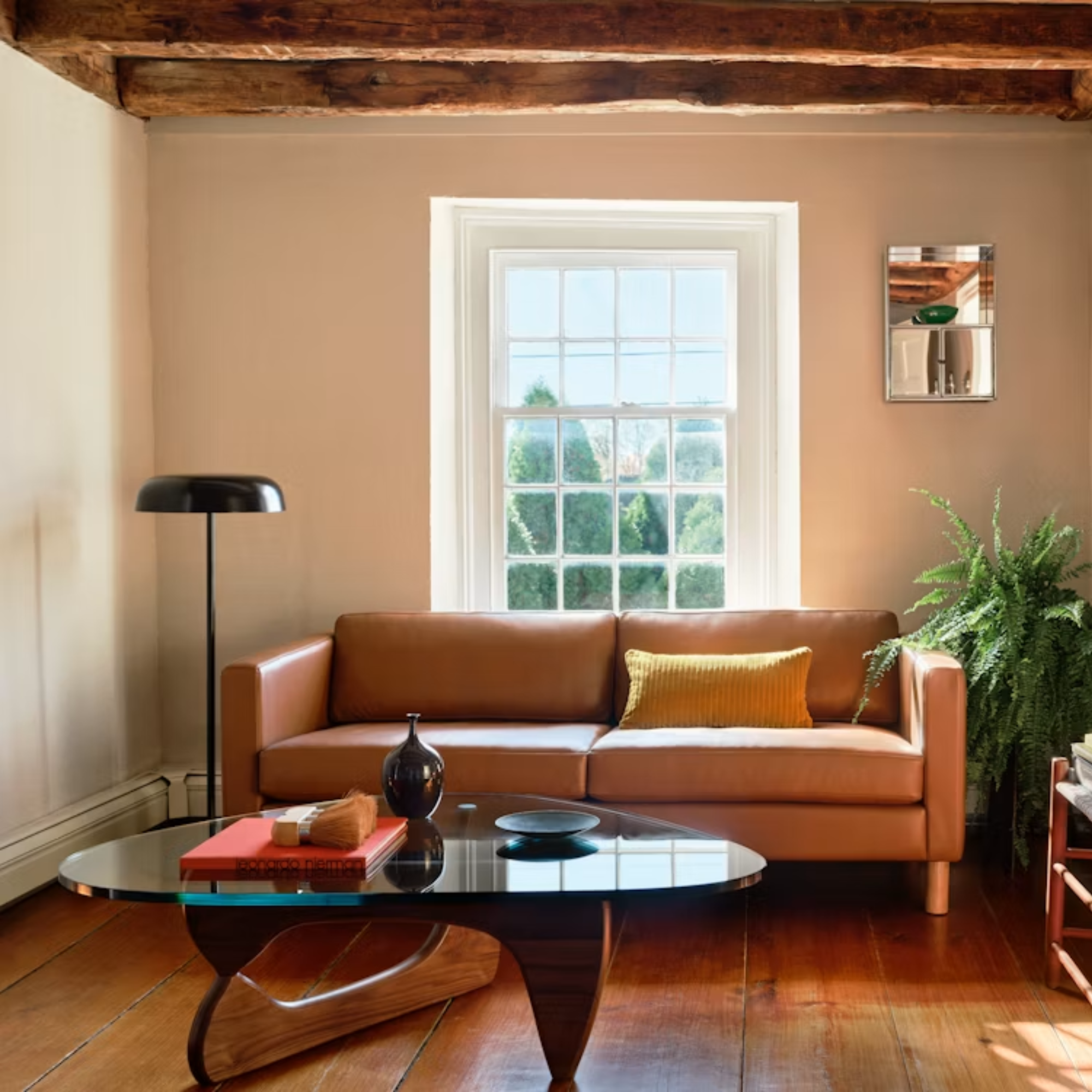 The walnut Noguchi Table from Herman Miller in a living space next to a floor lamp and sofa.