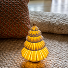 The Christmas Tree Cordless Table Lamp from Lladro in a living room on top of a rug.