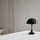 The black Panthella 160 Portable Lamp from Louis Poulsen in a dining room on top of a table.