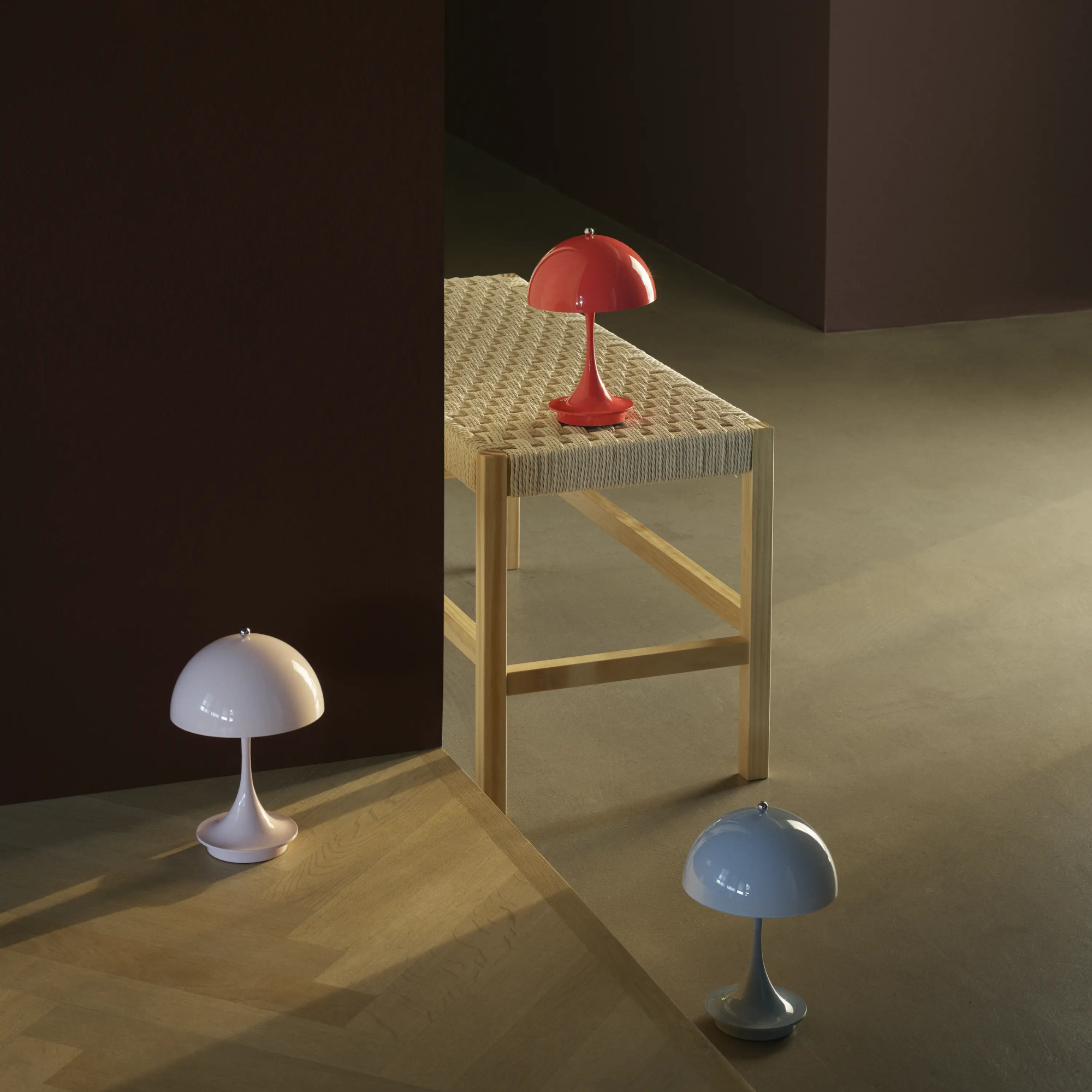 The coral Panthella 160 Portable Lamp from Louis Poulsen in a living area with a bench and two other cordless lights.
