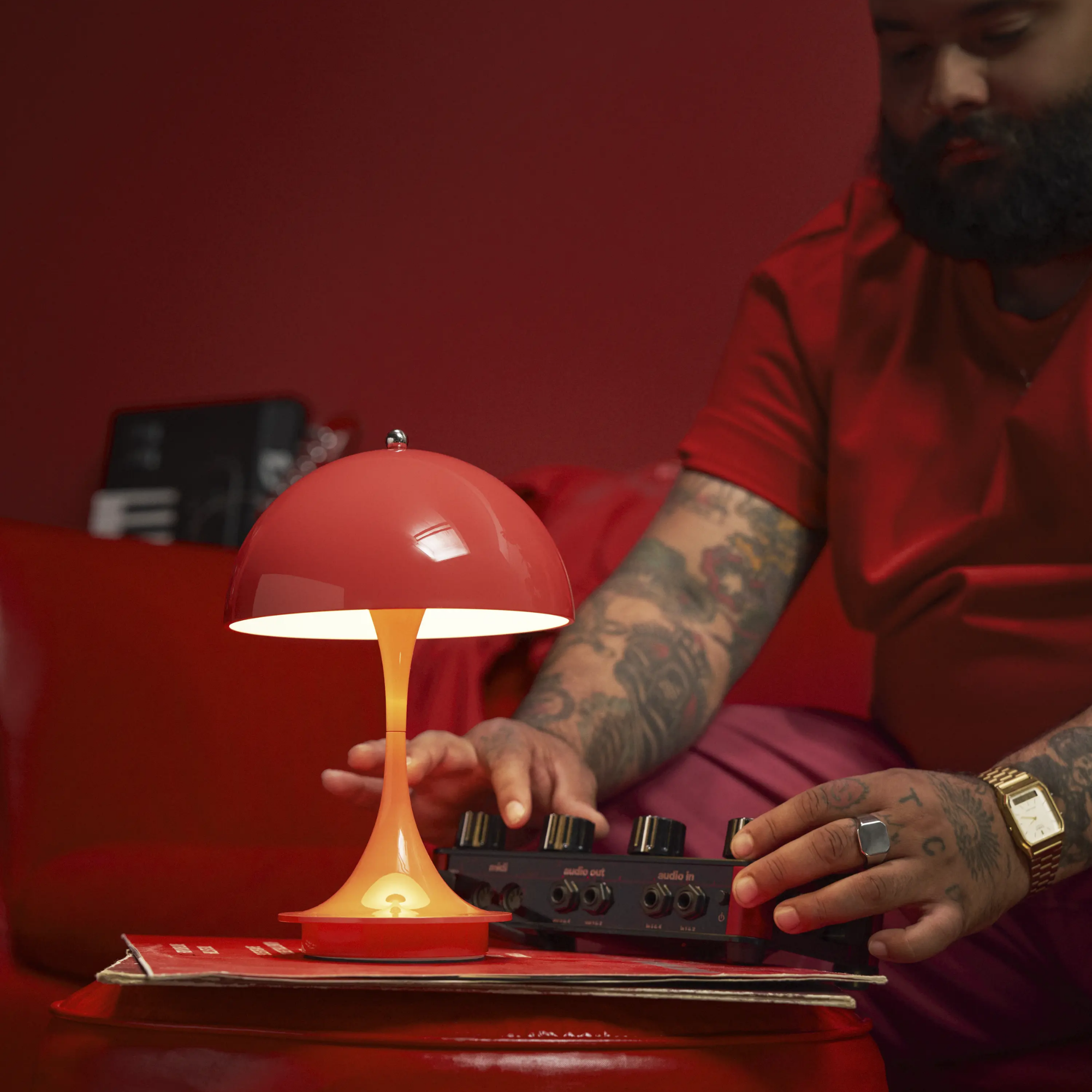 The coral Panthella 160 Portable Lamp from Louis Poulsen in a living room with a man in a red shirt and pants.