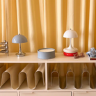 The grey opal Panthella 160 Portable Lamp from Louis Poulsen in a family area on top of a storage piece.