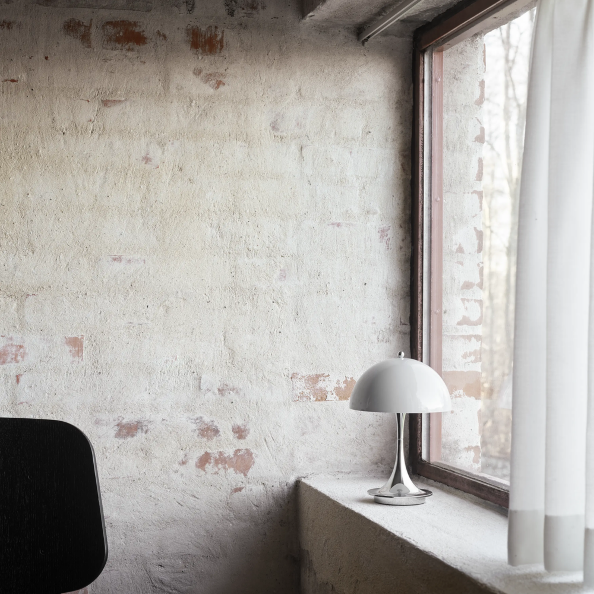 The grey opal Panthella 160 Portable Lamp from Louis Poulsen in a living room on the windowsill.