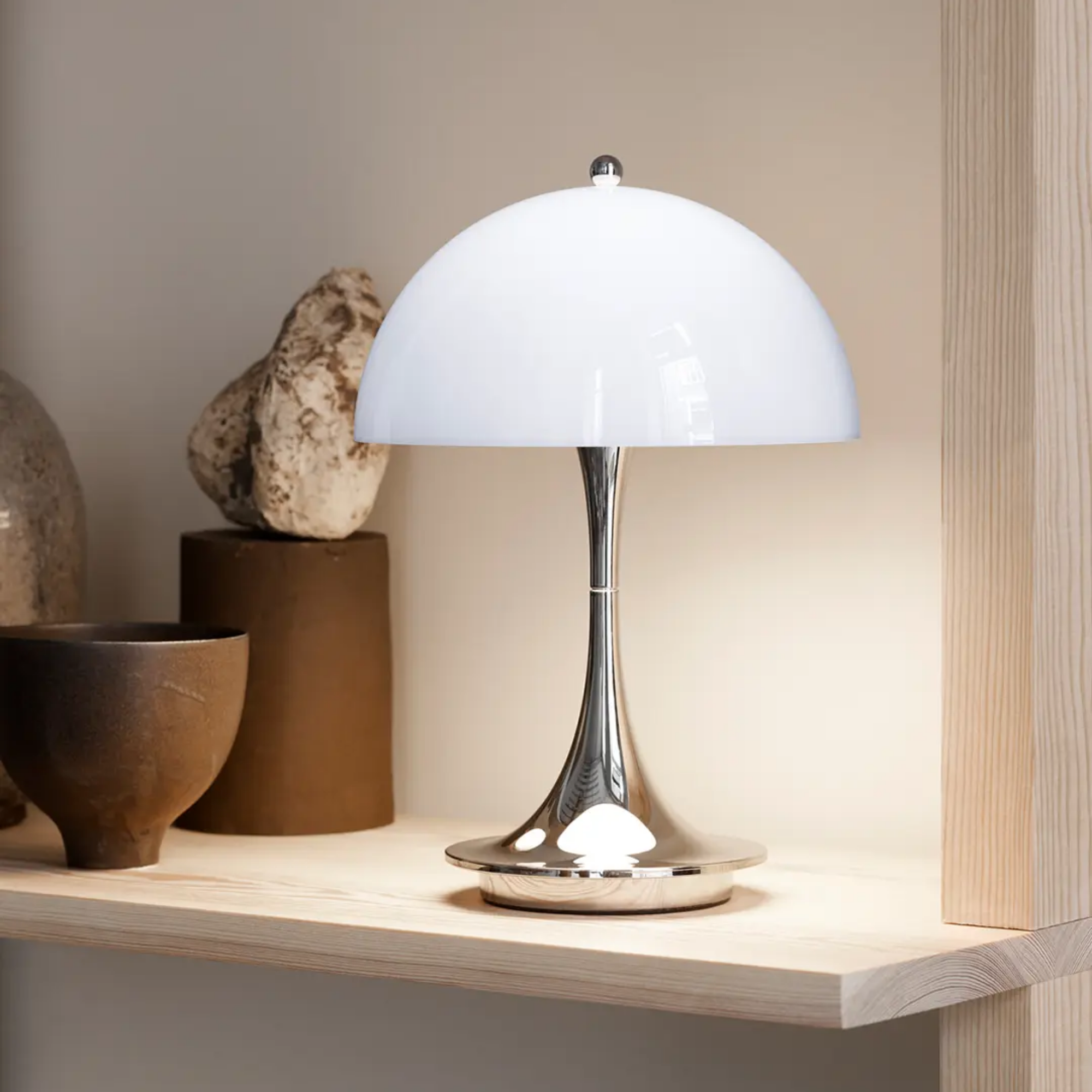The grey opal Panthella 160 Portable Lamp from Louis Poulsen in a primary bedroom on a shelf.