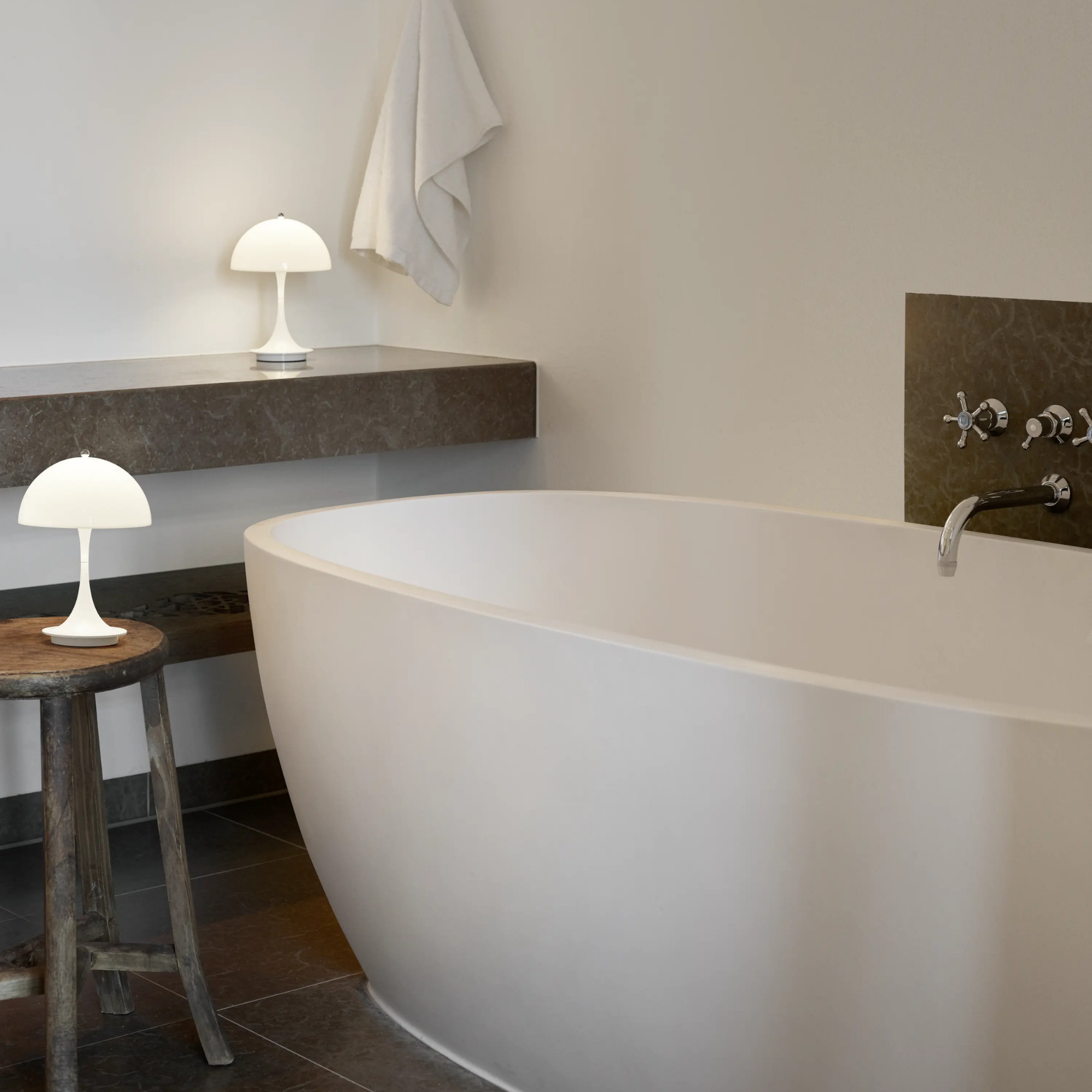 The opal Panthella 160 Portable Lamp from Louis Poulsen in a bathroom on a stool and a counter.