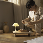 The opal beige Panthella 160 Portable Lamp from Louis Poulsen in a living room, turned on, being used.