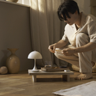 The opal beige Panthella 160 Portable Lamp from Louis Poulsen in a living space, turned off, being used on a tray.