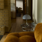 The grey opal Panthella 250 Portable Lamp from Louis Poulsen on a side table beside a sofa in a family area.