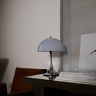 The grey opal Panthella 250 Portable Lamp from Louis Poulsen in a home offce on top of a table.