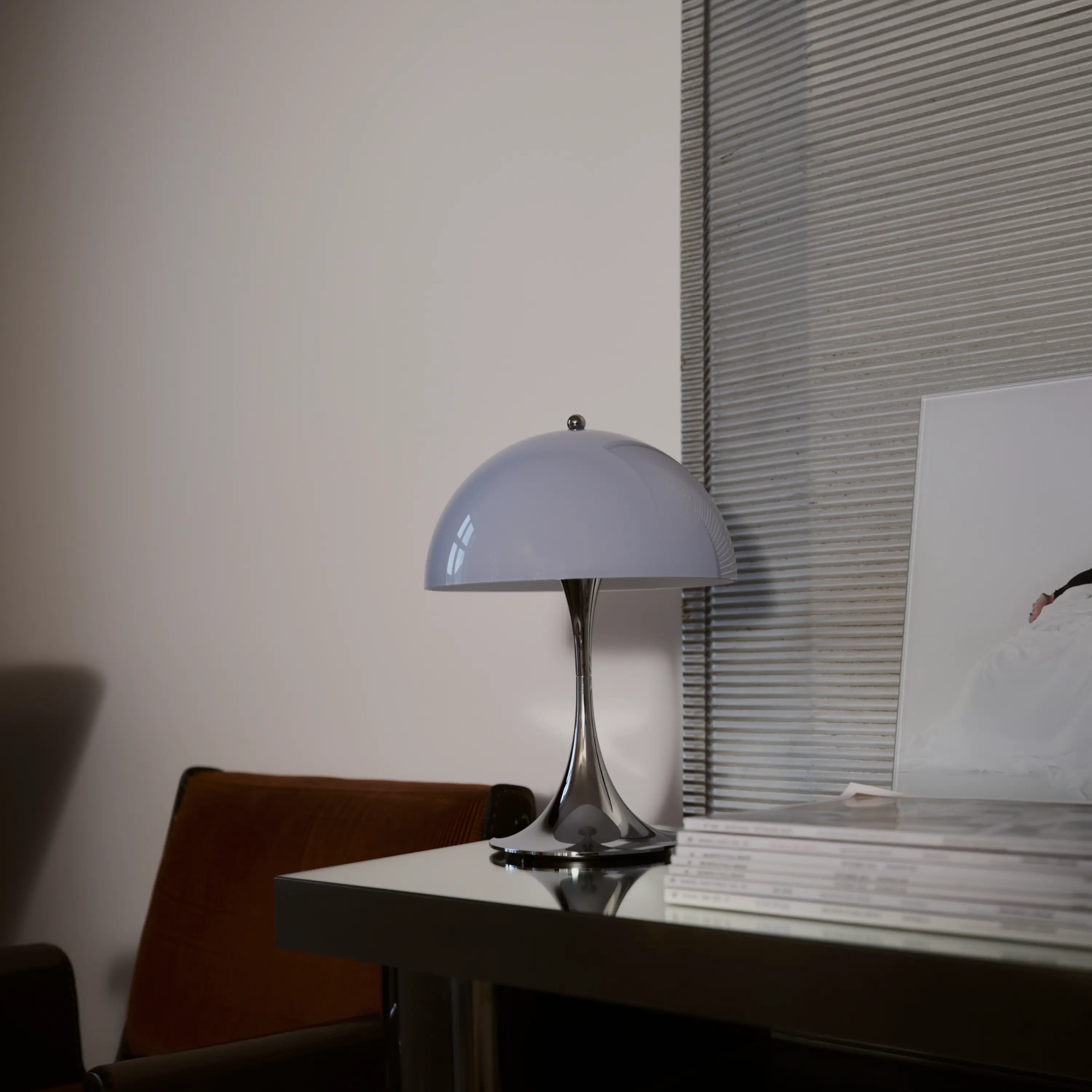 The grey opal Panthella 250 Portable Lamp from Louis Poulsen in a home offce on top of a table.