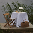 The opal Panthella 250 Portable Lamp from Louis Poulsen in a garden on top of a table with a cloth and a drink.