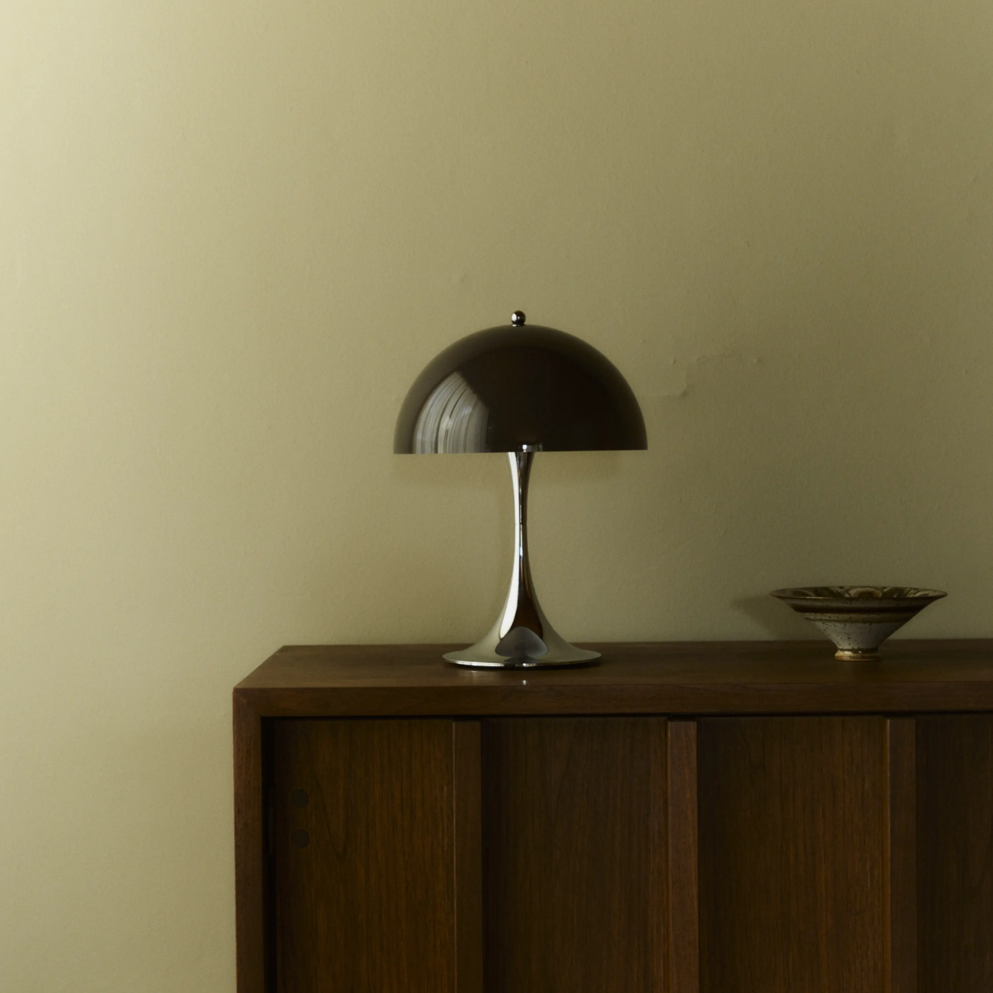 The 13.2 inch brown Panthella Portable Lamp: The Originals from Louis Poulsen in a living space on top of a wooden console.