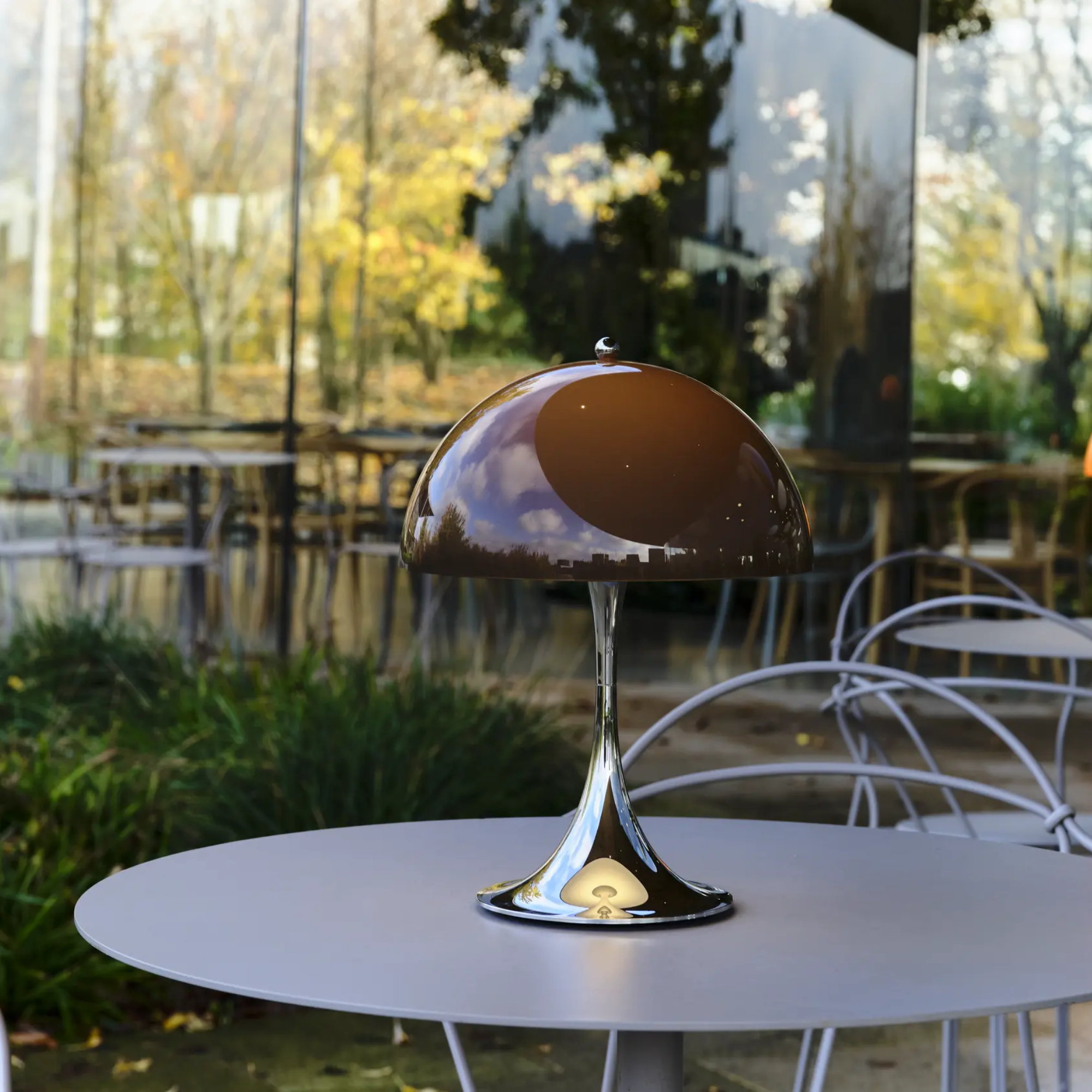 The 13.2 inch brown Panthella Portable Lamp: The Originals from Louis Poulsen on a dining table in an outdoor cafe.