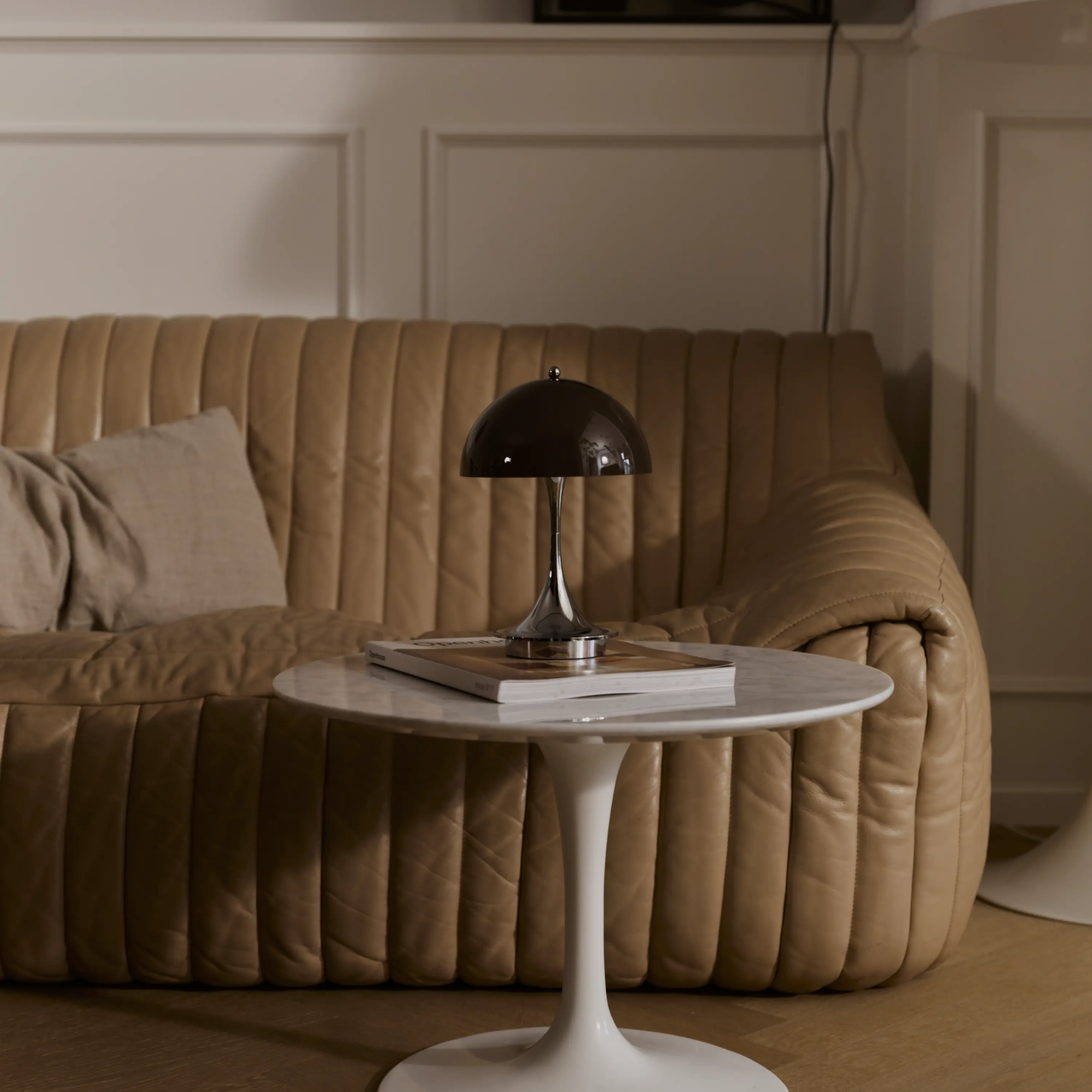 The 9.5 inch brown Panthella Portable Lamp: The Originals from Louis Poulsen in a living area on a table beside a couch.
