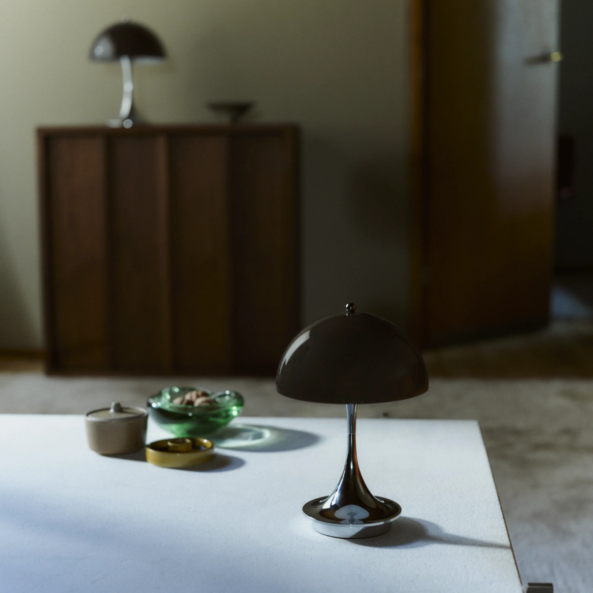 The 9.5 inch brown Panthella Portable Lamp: The Originals from Louis Poulsen in a living space on top of a coffee table.