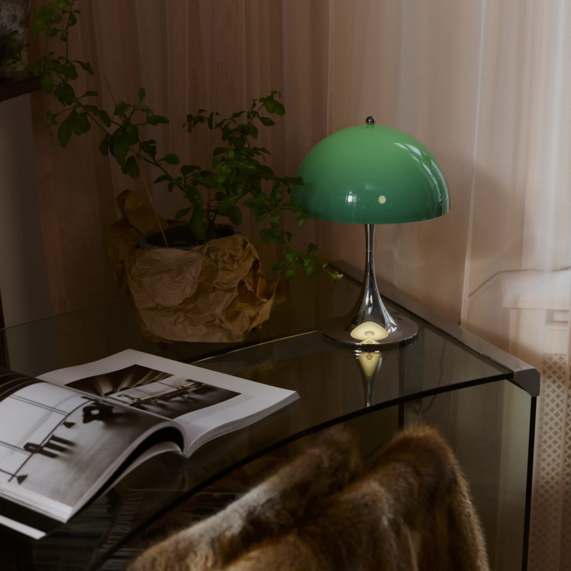 The 13.2 inch green Panthella Portable Lamp: The Originals from Louis Poulsen in a living room on top of a glass table.