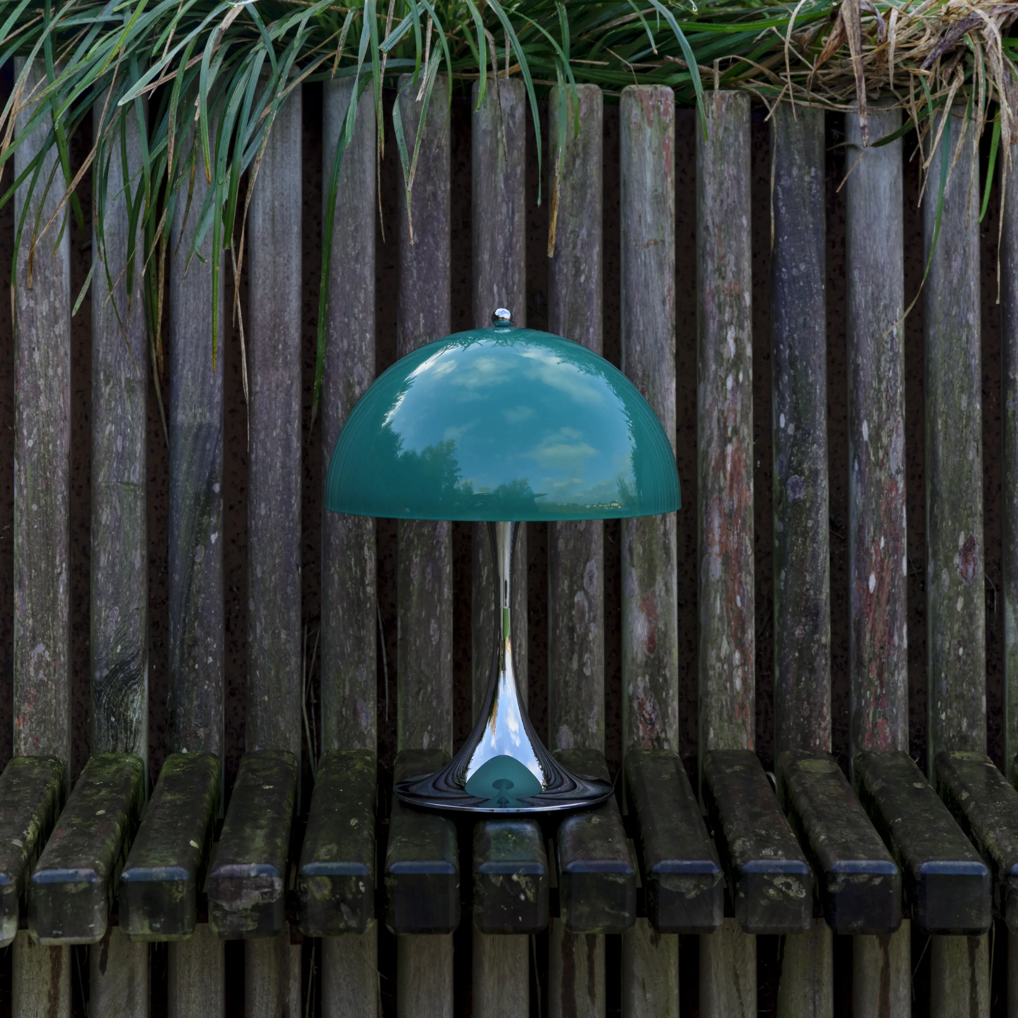 The 13.2 inch green Panthella Portable Lamp: The Originals from Louis Poulsen in an outdoor terrace beside grass.