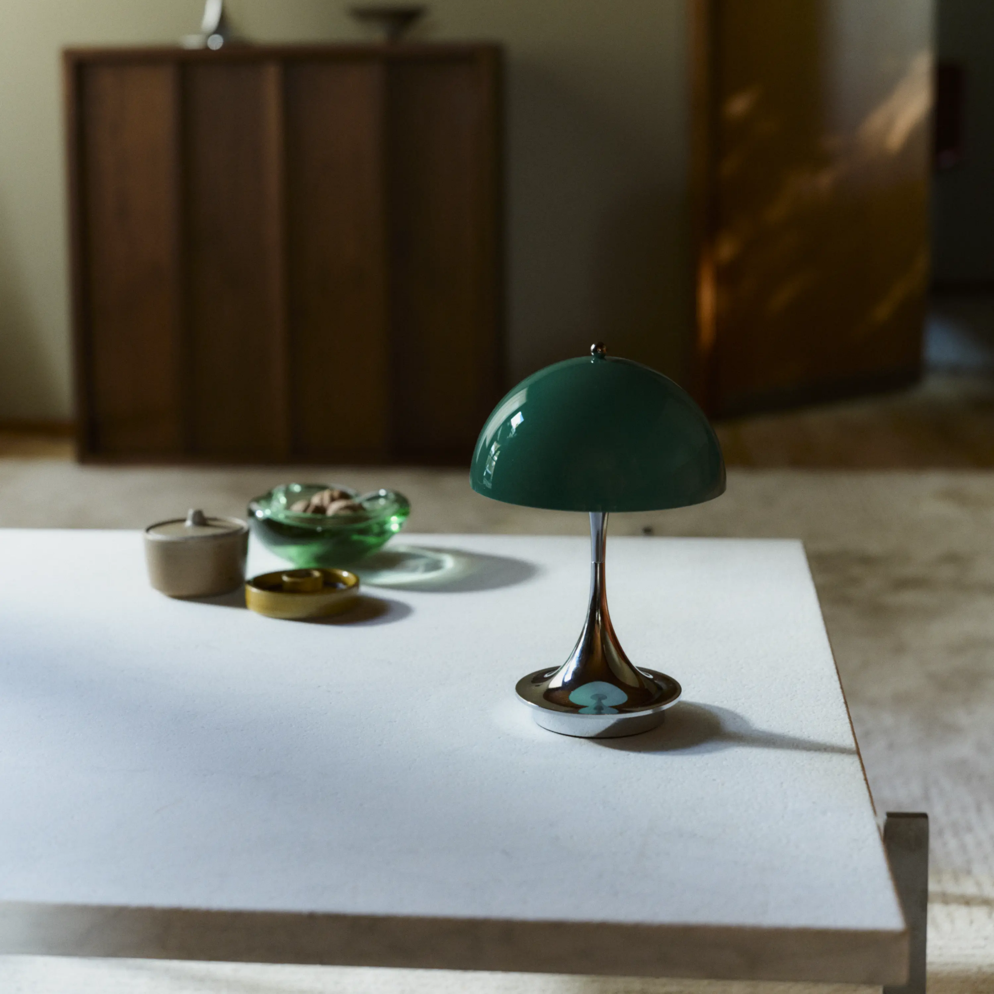 The 9.5 inch green Panthella Portable Lamp: The Originals from Louis Poulsen in a living space on top of a table.