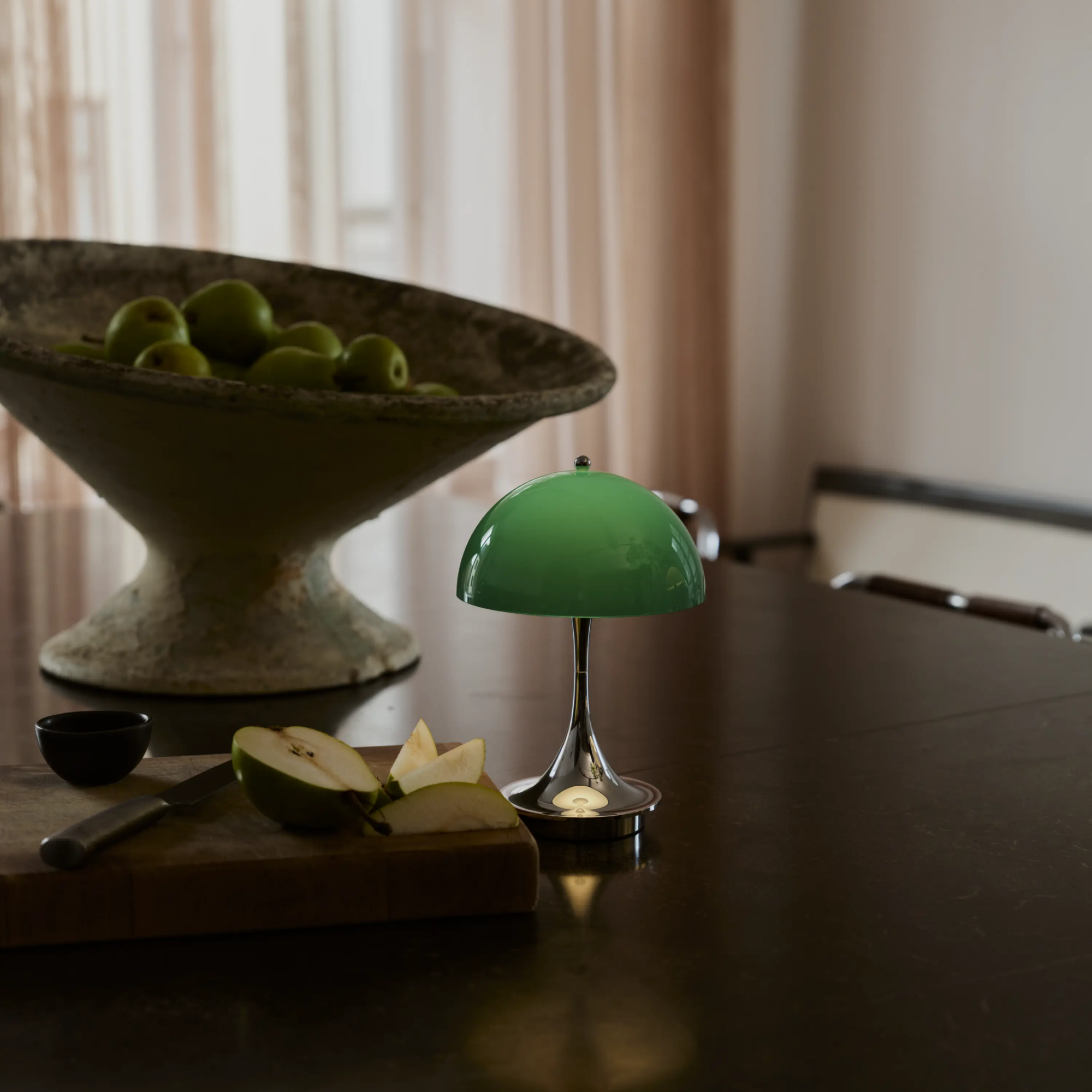 The 9.5 inch green Panthella Portable Lamp: The Originals from Louis Poulsen in a lounge on top of dining room table.