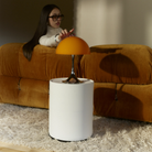 The 13.2 inch orange Panthella Portable Lamp: The Originals from Louis Poulsen in a family area being used by a woman on a couch.