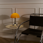 The 13.2 inch orange Panthella Portable Lamp: The Originals from Louis Poulsen in a living space beside a lounge chair.