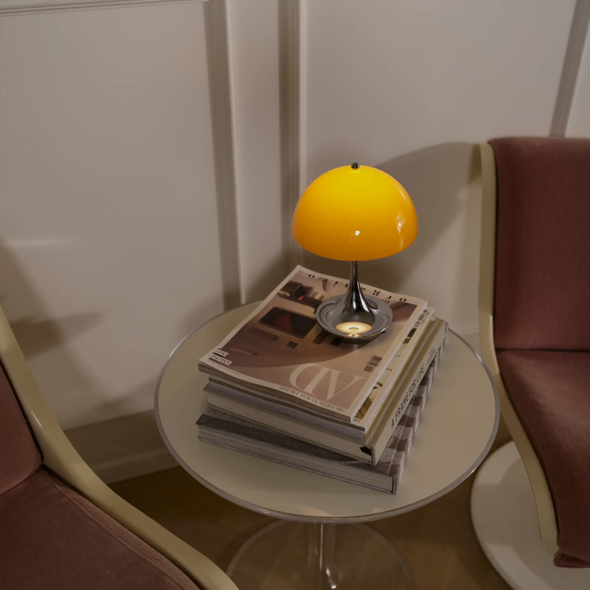 The 9.5 inch orange Panthella Portable Lamp: The Originals from Louis Poulsen beside two lounge chairs in a living room.