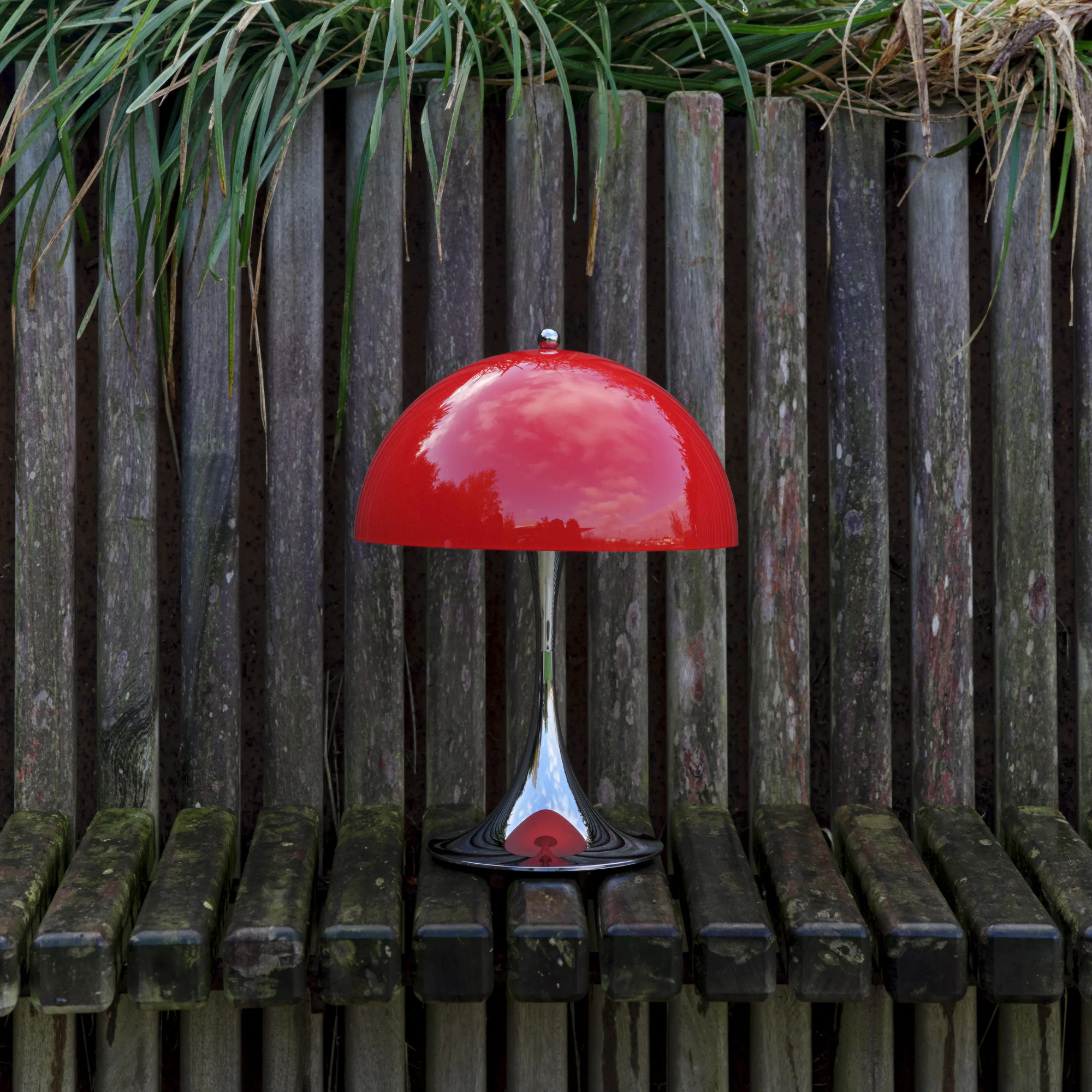 The 13.2 inch red Panthella Portable Lamp: The Originals from Louis Poulsen in an outdoor family space lighting up some seating.