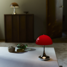 The 9.5 inch red Panthella Portable Lamp: The Originals from Louis Poulsen in a home office on top of a table.