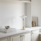 The brass PH 2/1 Portable Lamp from Louis Poulsen in a home office.