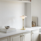 The brass PH 2/1 Portable Lamp from Louis Poulsen in a living room on top of a shelf.