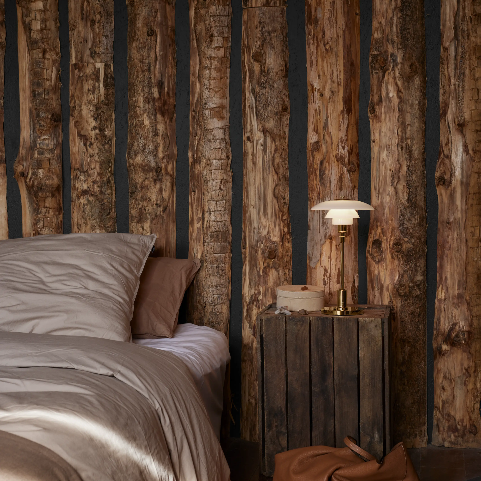 The brass PH 2/1 Portable Lamp from Louis Poulsen in a primary bedroom on top of a wooden bedside table.