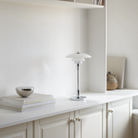 The chrome PH 2/1 Portable Lamp from Louis Poulsen in a family area on a bookshelf.